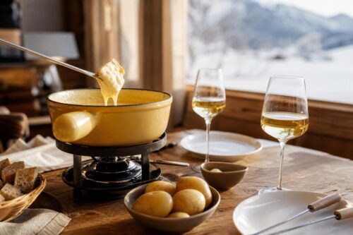 Fondue savoyarde avec pain, pommes de terre et verres de vin blanc sec