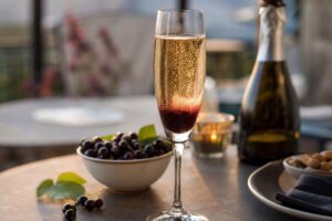 Kir royal dans une flûte avec bulles et cassis sur une table d’apéritif
