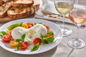 Burrata avec tomates, basilic, pain grillé, un verre de vin blanc et un verre de rosé, sans texte ni personne