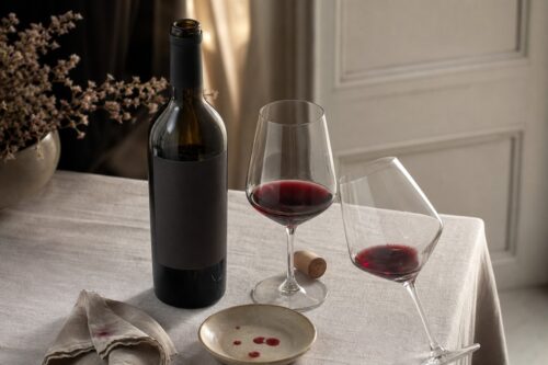 Bouteille de vin rouge ouverte avec deux verres sur une table claire