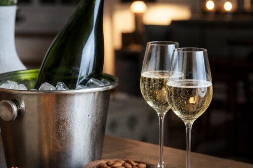 Bouteille de champagne sans étiquette dans un seau à glace avec deux verres et bouchées apéritives, sans texte ni personne