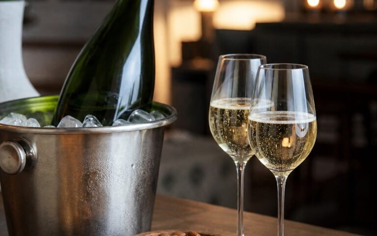 Bouteille de champagne sans étiquette dans un seau à glace avec deux verres et bouchées apéritives, sans texte ni personne