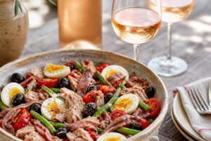 Salade niçoise avec thon, anchois, œufs, tomates, olives et deux verres de rosé sans texte ni personne