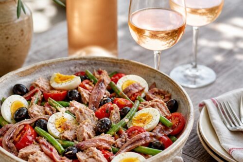 Salade niçoise avec thon, anchois, œufs, tomates, olives et deux verres de rosé sans texte ni personne