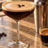 Espresso Martini mousseux dans une coupe avec shaker et grains de café